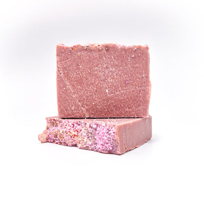 Two bars of handmade blush pink colored natural soap. One lying flat to show texture, one upright.