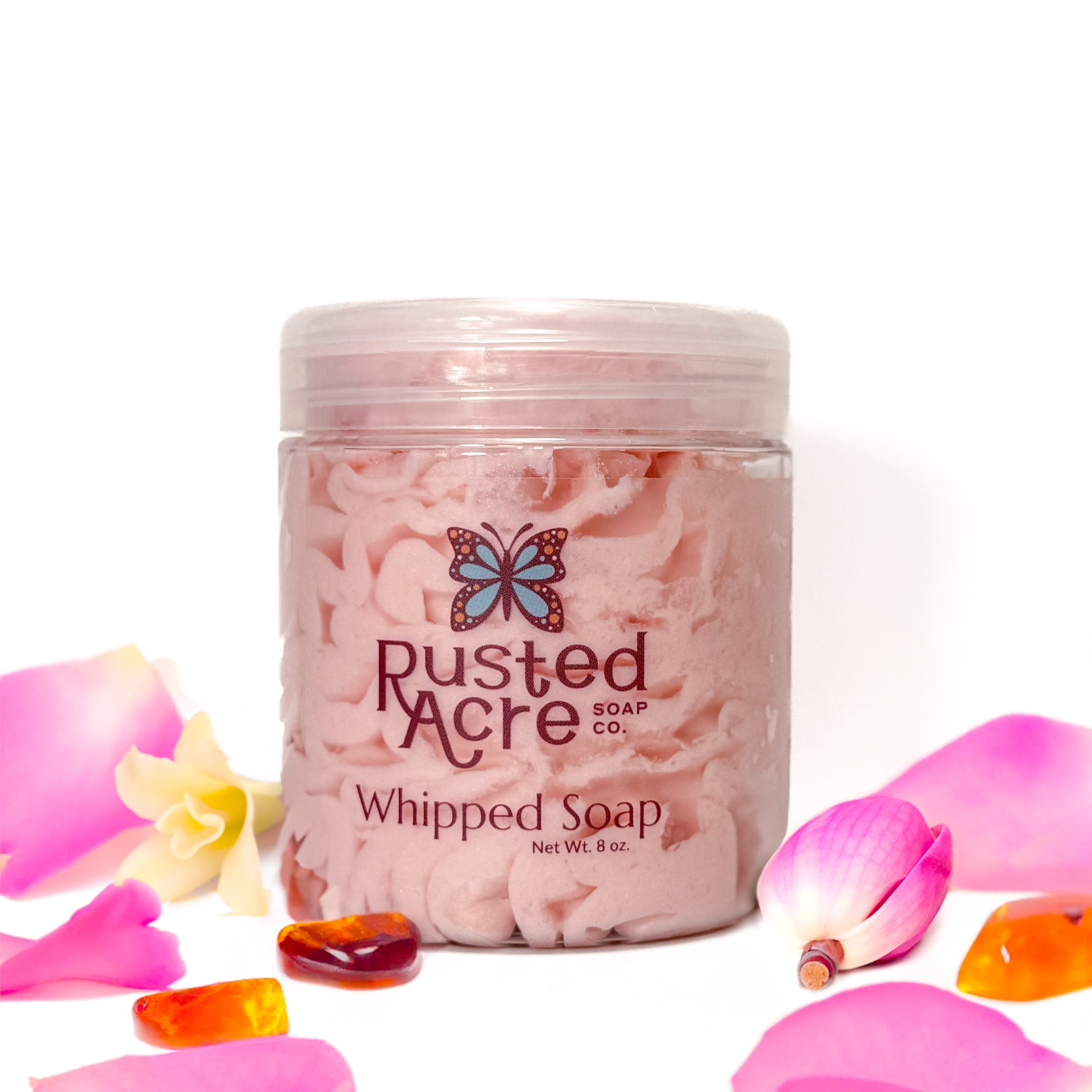 Jar of Rusted Acre Soap Company's vegan amber kiss whipped soap. Pink  soap in a reusable plastic jar in a lifestyle setting. 