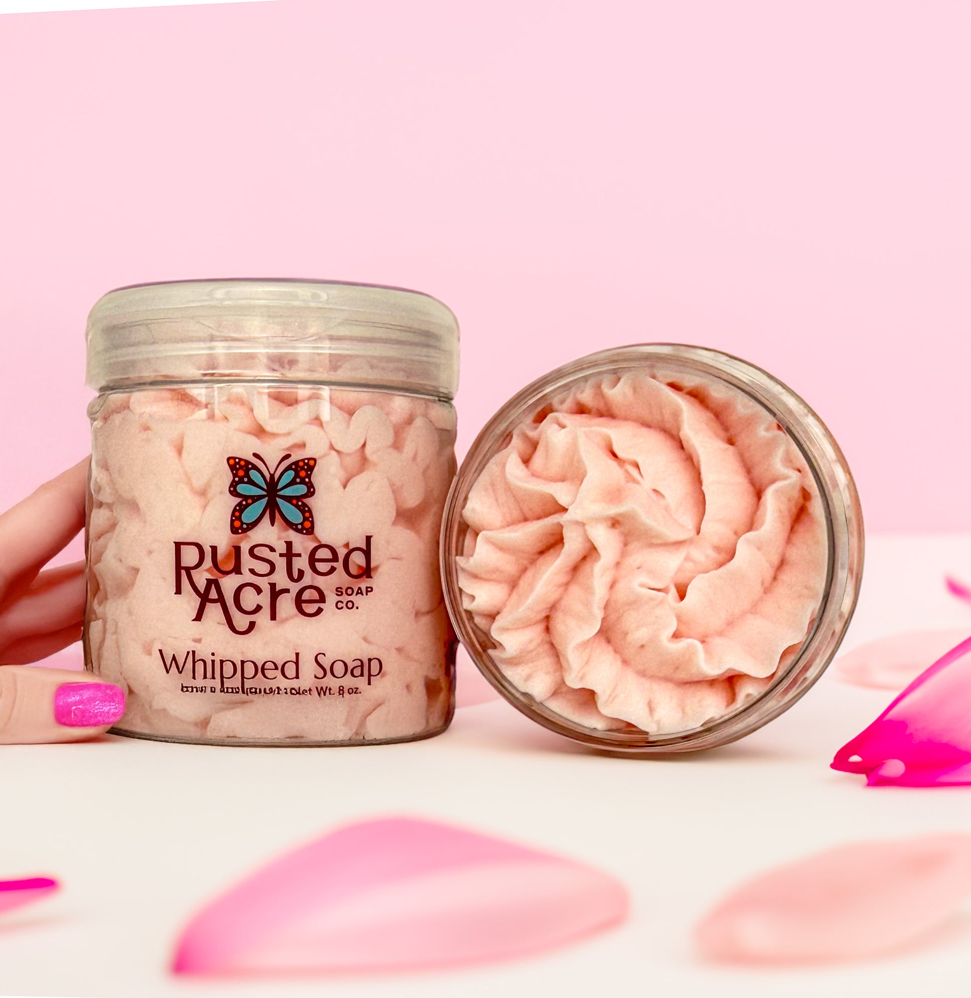 Two jars of Rusted Acre Soap Company's amber kiss whipped soap in a lifestyle image.