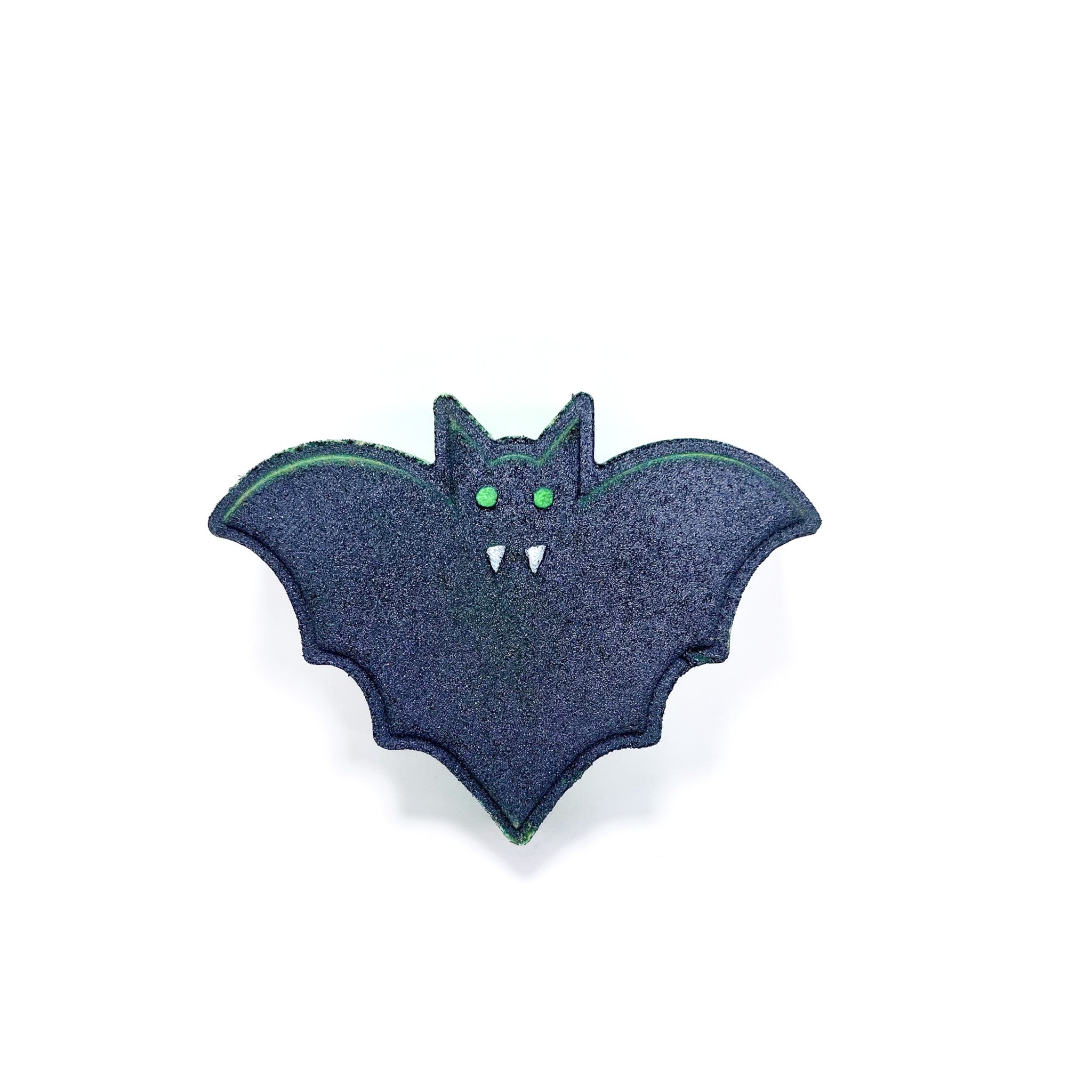 A green bat shaped bath bomb airbrushed black. Hand-painted green eye and white fangs by Rusted Acre Soap Co.