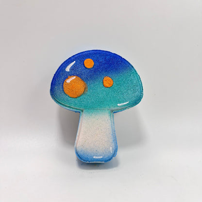 A mushroom shaped bath bomb. Airbrushed from bottom to top teal to blue. Hand-painted orange dots.