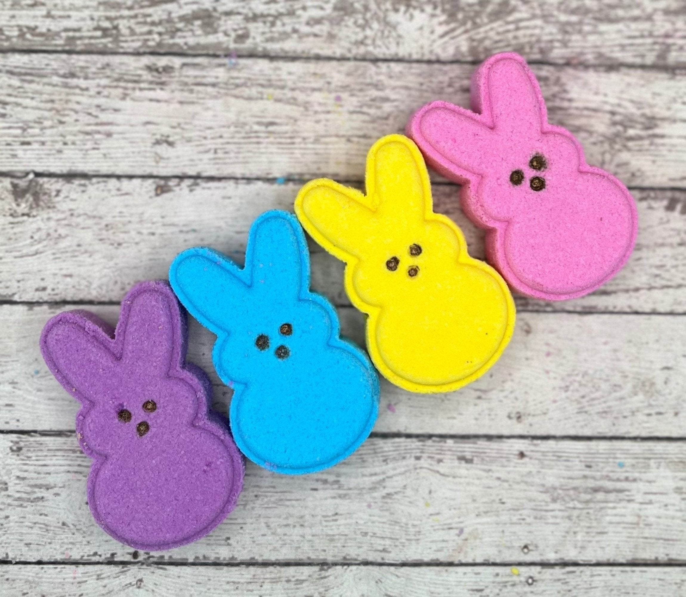 Four Bunny bath bombs handmade by Rusted Acre Soap Co. Colors are, one purple, one blue, one yellow, one pink.