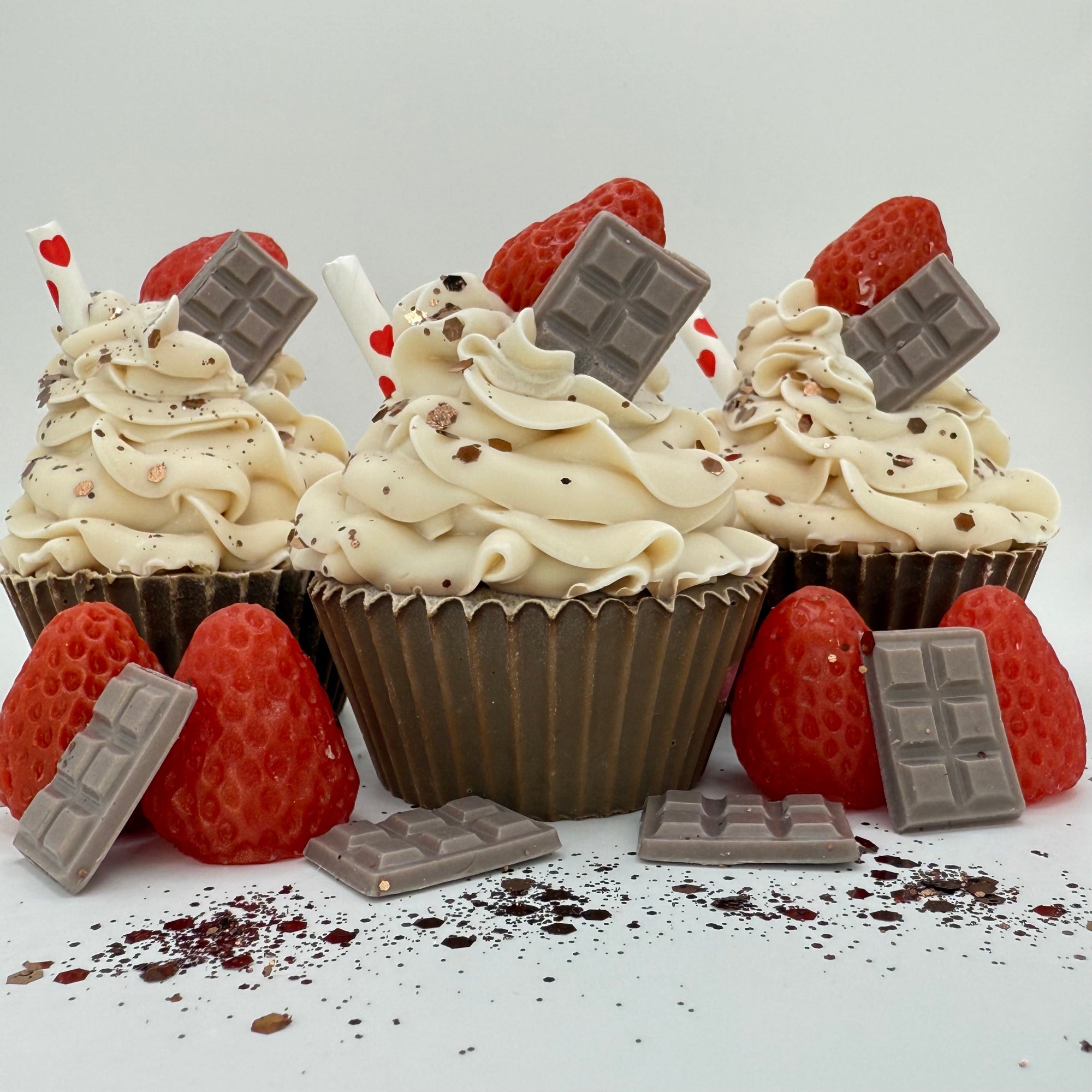 Three handmade chocolate strawberry cupcake soaps from Rusted Acre Soap Company. Chocolate brown cake and white frosting. Topped with chocolate soap bar, strawberry shaped soap and a straw.