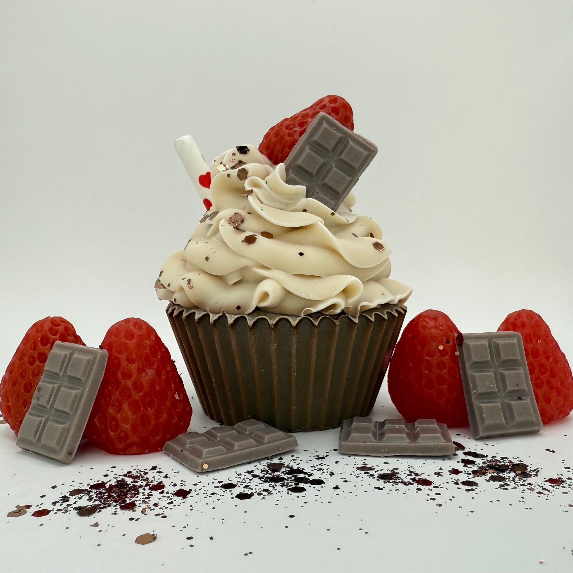 One cupcake shaped soap with brown cake and white icing. Topped with soap chocolate, red strawberry a paper straw and brown sprinkles.