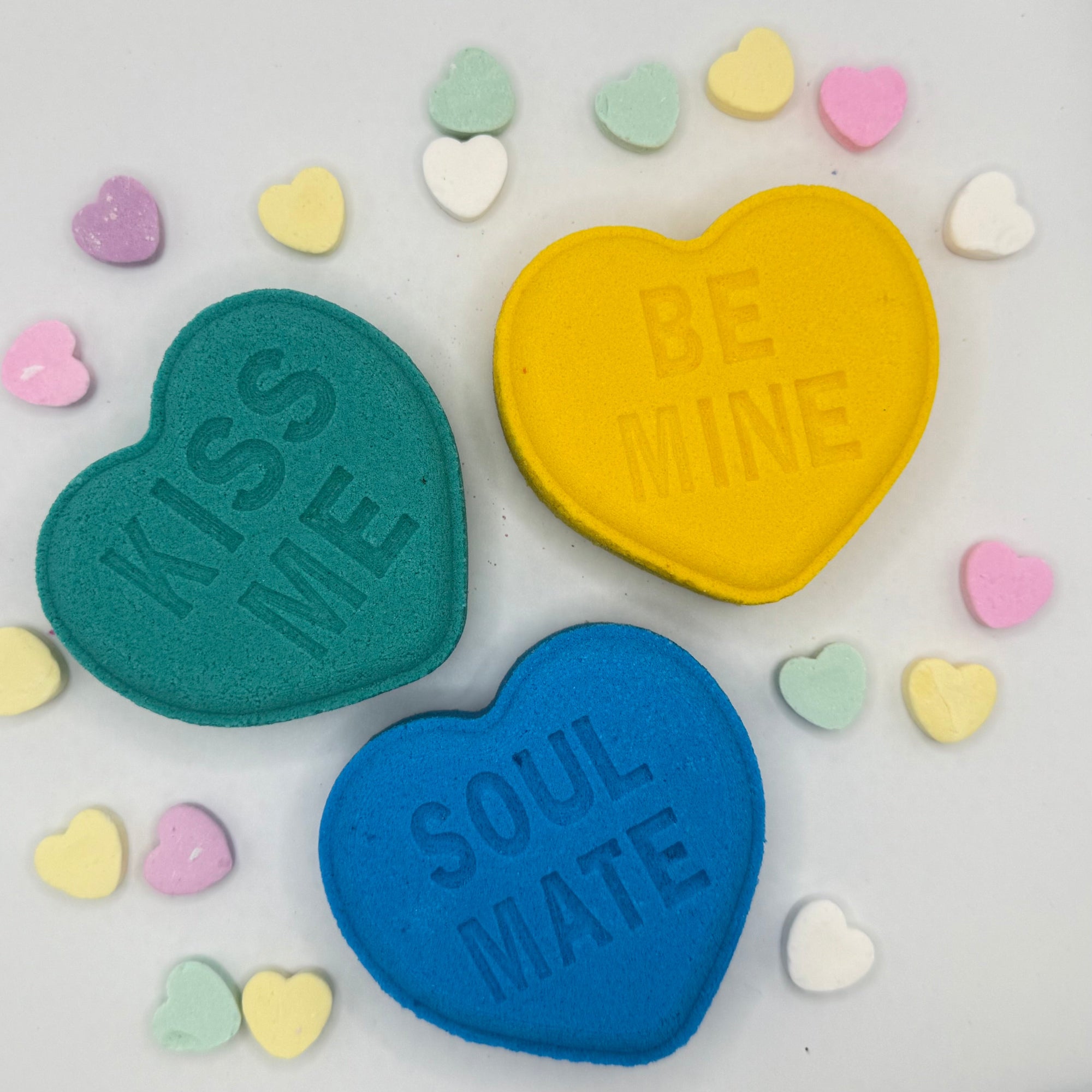 Heart bath bombs with messages from Rusted Acre Soap Company. Three hearts in green, blue and yellow.