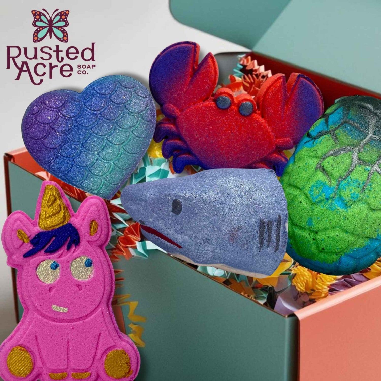 A subscription box of bath bombs for kids from Rusted Acre Soap Co. Various hand-painted bath bombs in a box.