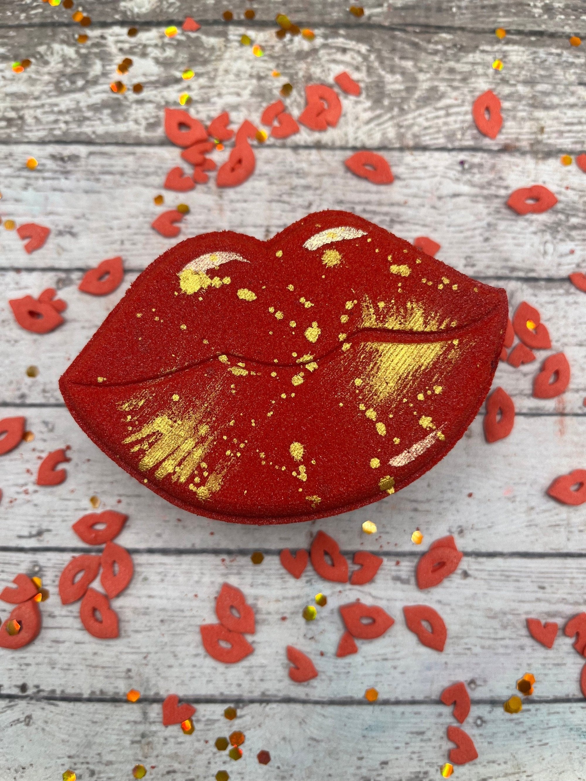 One red lips shaped bath bomb. Brushed and splattered with gold. Displayed with red lip sprinkles!