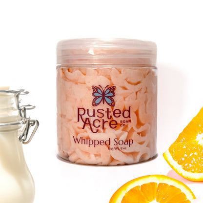 Jar of Rusted Acre Soap Company's vegan orange dream whipped soap.  Orange soap in a reusable plastic jar in a lifestyle setting. 