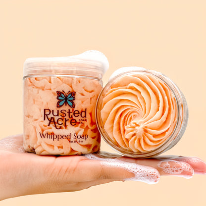 Two jars of Rusted Acre Soap Company's orange dream whipped soap in a lifestyle image.