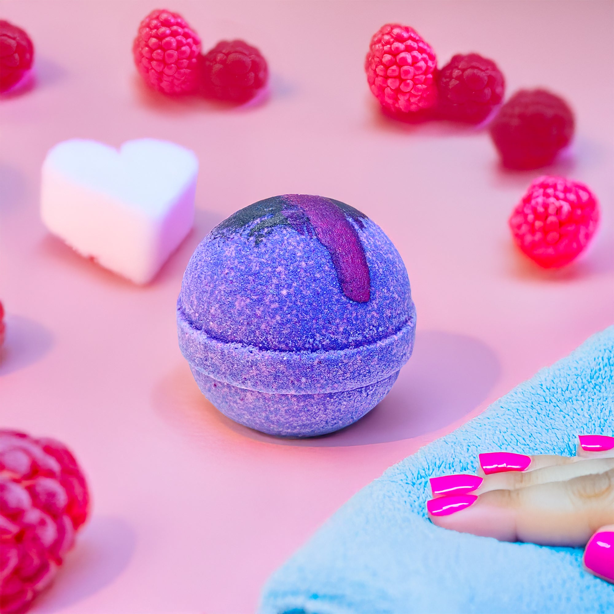 Rusted Acre Soap Company's raspberry vanilla bath bomb on the counter by a folded washcloth.