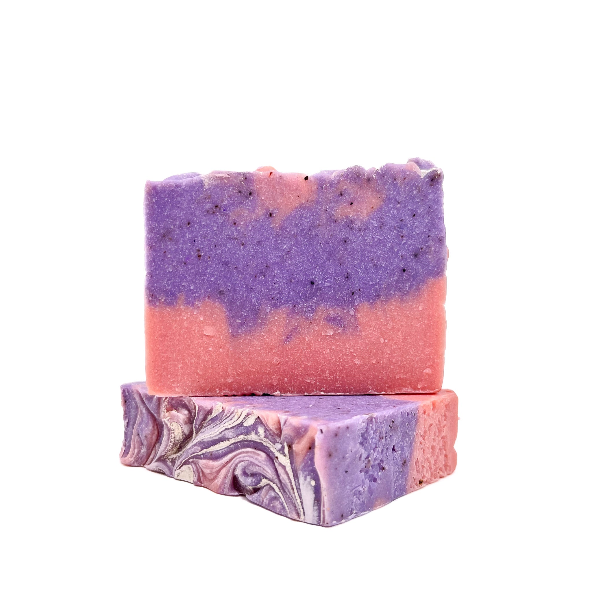 Two handmade raspberry vanilla bar soaps. Pink on the bottom, purple and pink swirled upper. Topped with shimmer. One top facing to show texture.