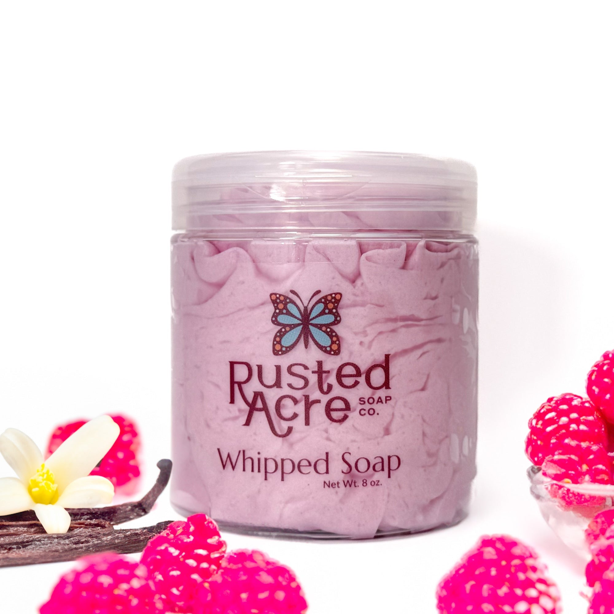 Jar of Rusted Acre Soap Company's vegan raspberry vanilla whipped soap. Pink soap in a reusable plastic jar in a lifestyle setting. 