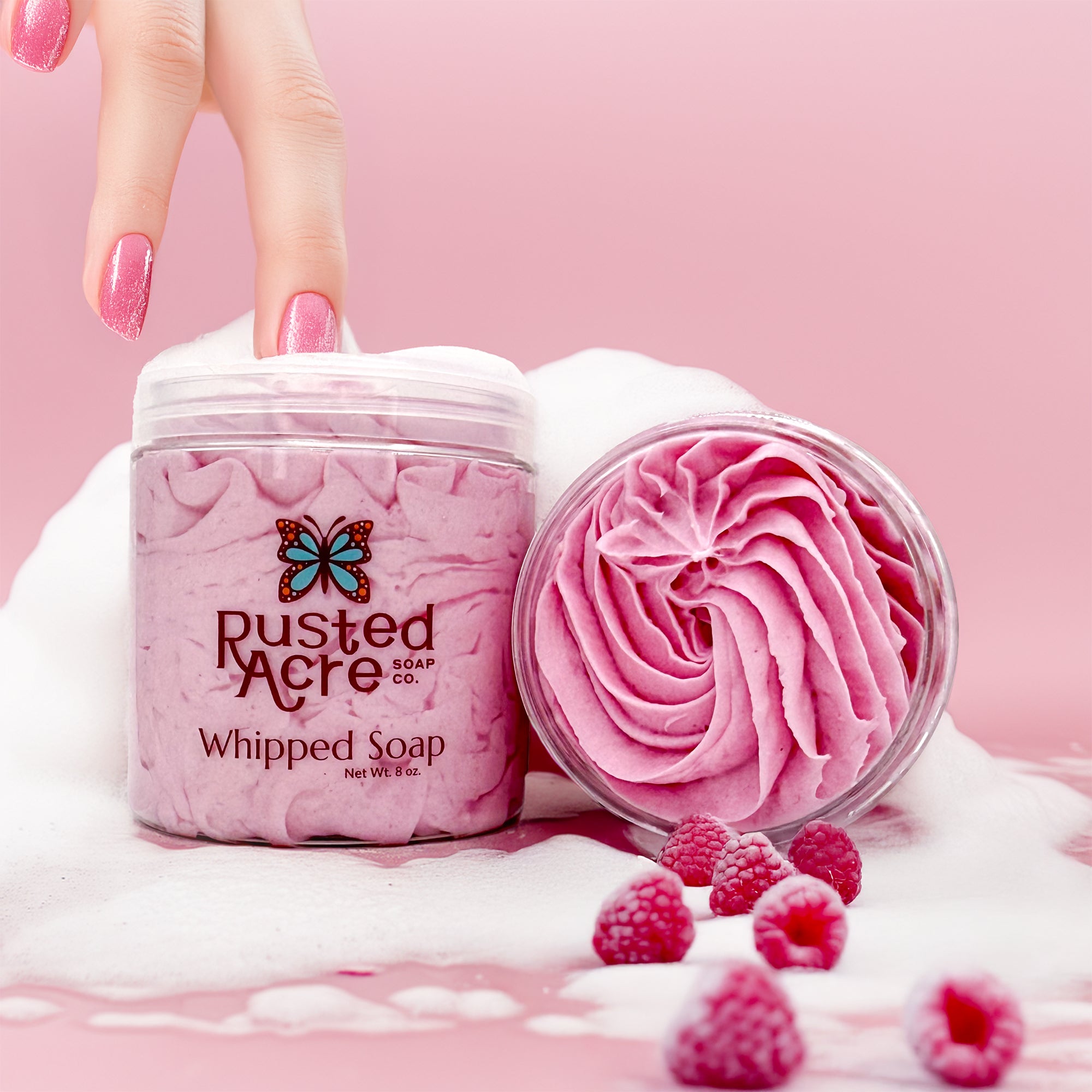 Two jars of Rusted Acre Soap Company's raspberry whipped soap in a lifestyle image.