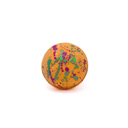 Round bright orange bath bomb splattered with green and purple mica.