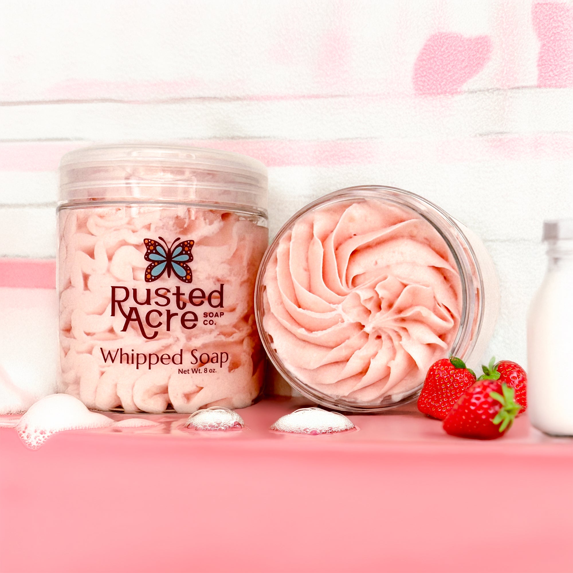 Two jars of Rusted Acre Soap Company's strawberries and cream whipped soap in a lifestyle image.