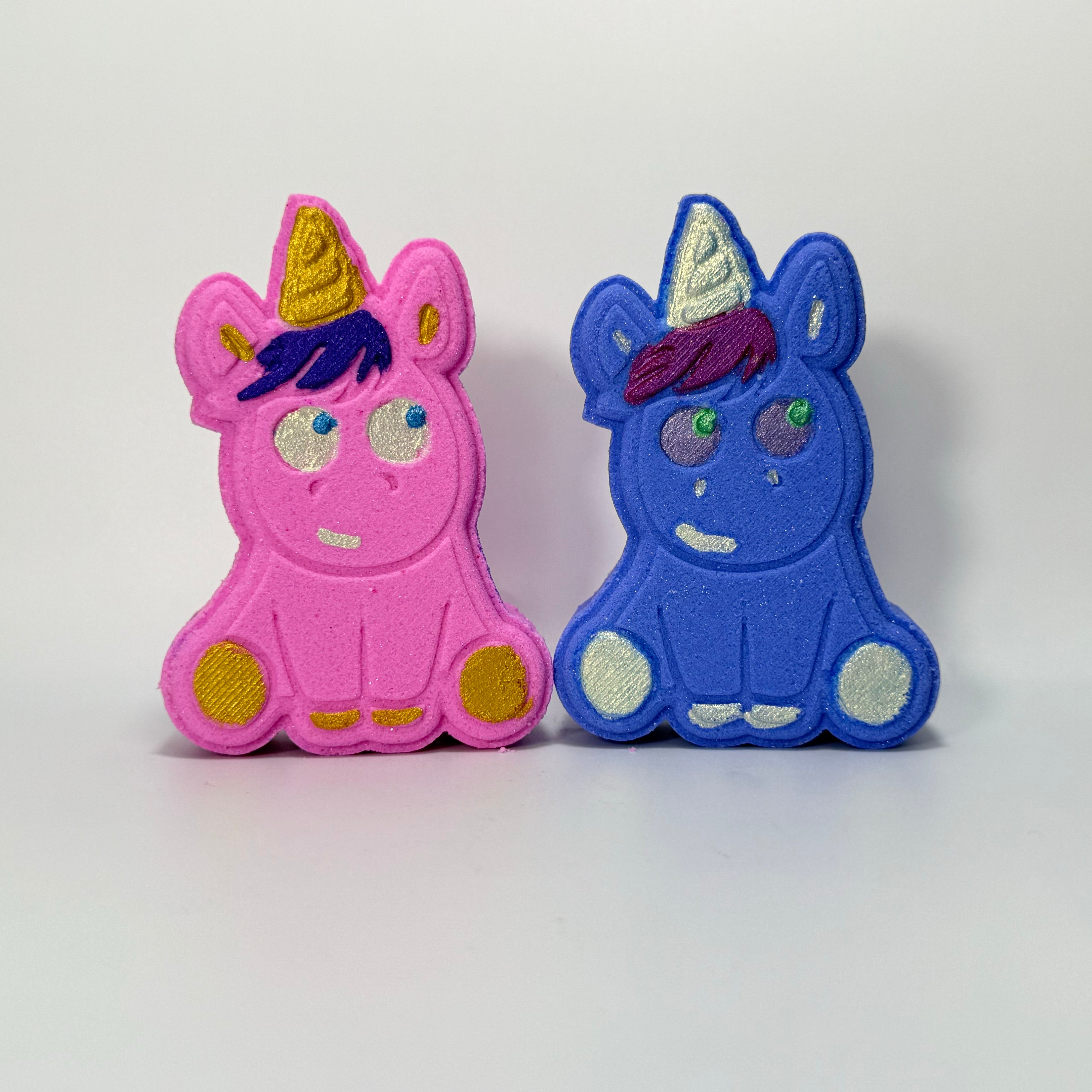 One pink unicorn with purple hair, gold horn, and blue eyes and one purple unicorn with teal hair, silver horn and blue eyes.