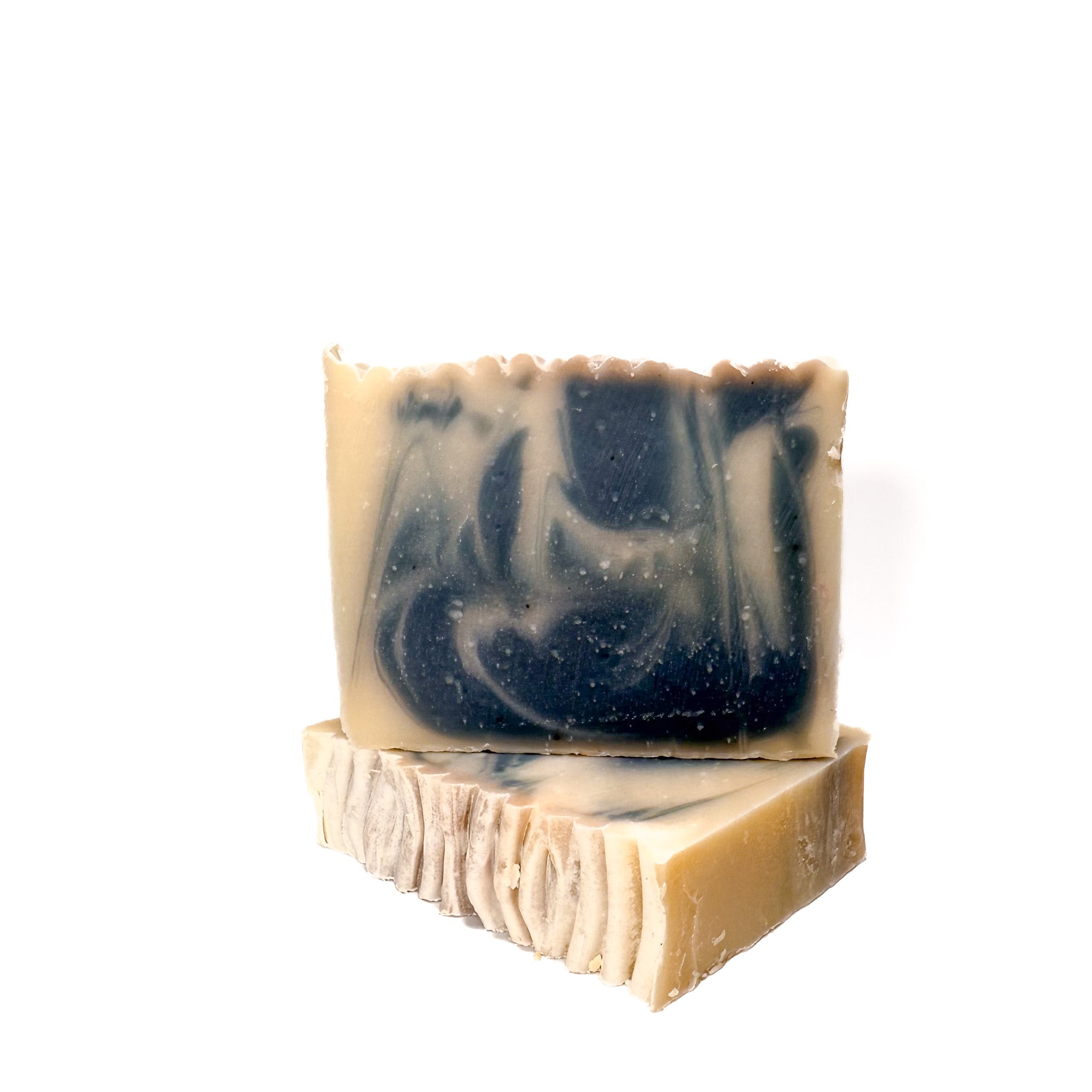 Two bars of handmade soap called zephyr. The colors are gray and natural tan swirled. One lying flat and one standing.